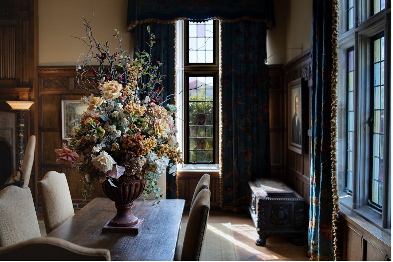 Interior of living room with flowers in vase on wooden table and fenced windows in sunlight
