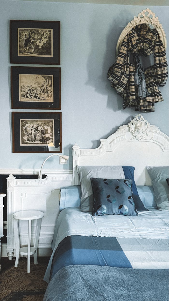 Vintage-inspired bedroom with ornate headboard, blue bedding, and framed artwork.