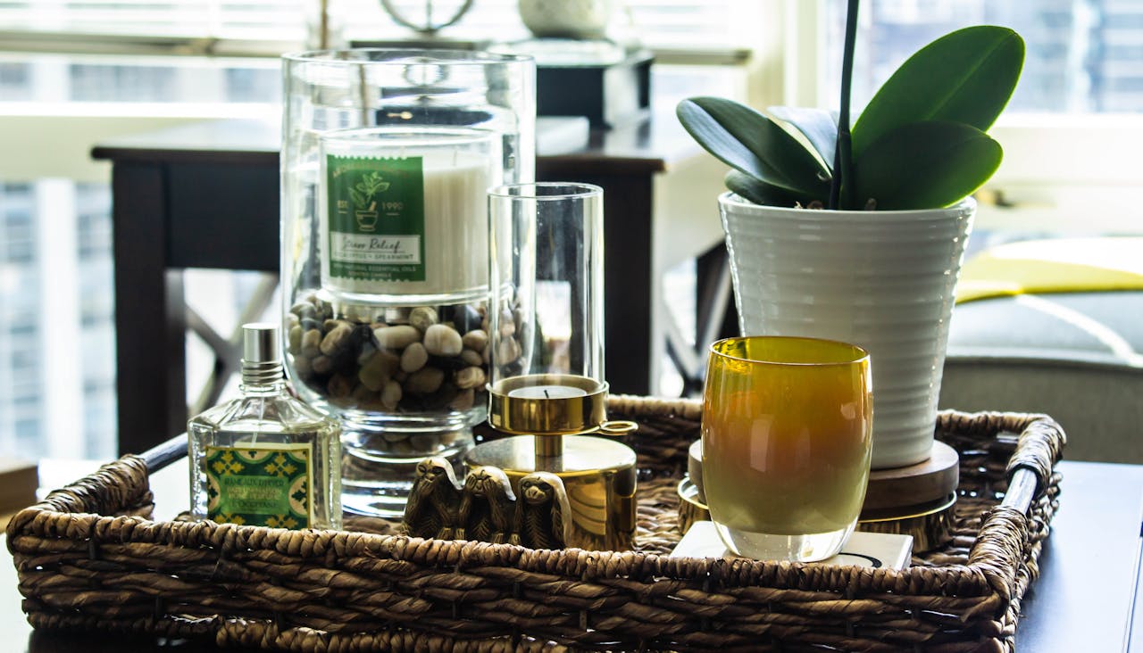 A stylish indoor arrangement with candles, glassware, and plants on a woven tray, perfect for modern home decor.