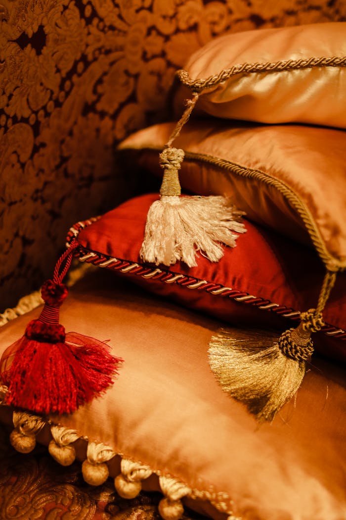 Luxurious throw pillows with tassels stacked in a warm, cozy setting.